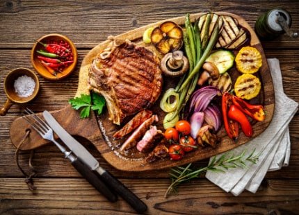 BBQ grilled dishes on a wooden board with vegetables