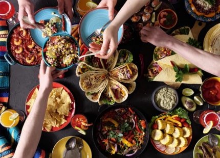 People sharing food over a Mexican style spread of food