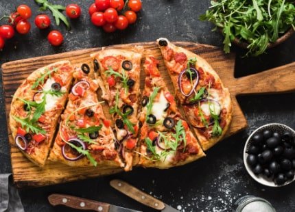 Flatbread pizza sliced up on a wooden board